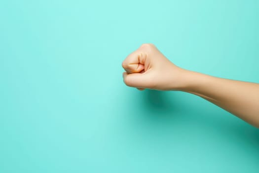 Two hands engage in a fist bump gesture against a clean turquoise background, conveying a sense of camaraderie and unity. This moment captures friendship and positivity.