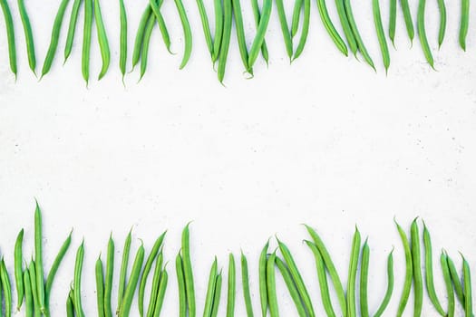 Creative scandinavian style flat lay top view of fresh green beans on white concrete table background copy space. Minimal house cooking concept template for blog or recipe book