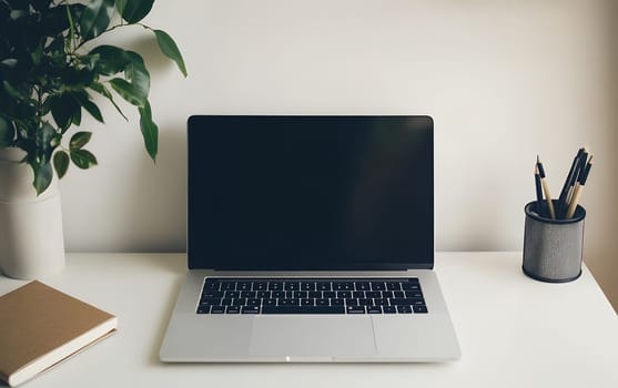 Modern workspace with laptop, potted plant, and stationery on white desk. Clean, organized home office setup with ample copy space.
