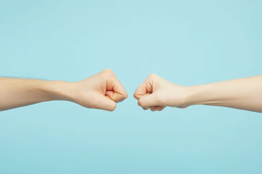 Two hands engage in a fist bump against a clean blue background, representing a moment of connection, celebration, or agreement. It highlights camaraderie and positivity.