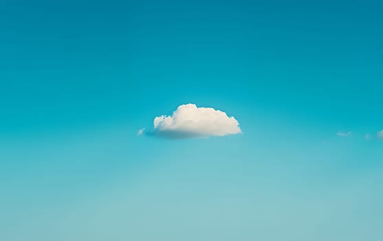 A single fluffy white cloud floats in a vast expanse of vibrant turquoise sky, offering ample copy space for text or design elements.
