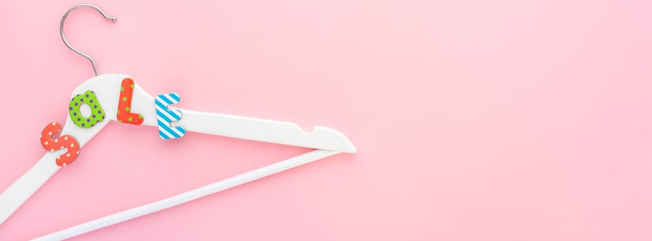 Creative top view flat lay white wooden hangers sale text pastel pink background copy space minimalism style. Template fashion feminine social media sale children store promo design shopping banner