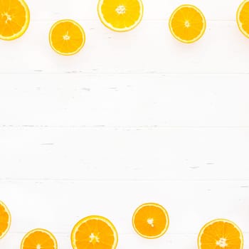 Creative scandinavian style flat lay top view of fresh orange fruit slices on white wooden table background with copy space. Minimal summer fresh citrus pattern for blog or recipe book