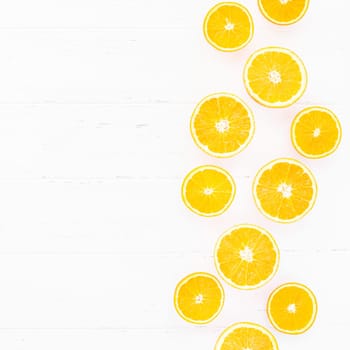 Creative scandinavian style flat lay top view of fresh orange fruit slices on white wooden table background with copy space. Minimal summer fresh citrus pattern for blog or recipe book
