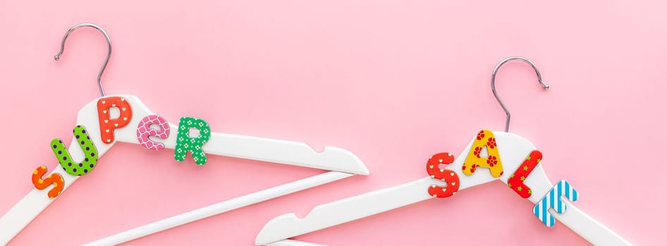 Creative top view flat lay white wooden hangers super sale text pastel pink background copy space minimalism style. Template fashion feminine blog social media sale store promo design shopping concept