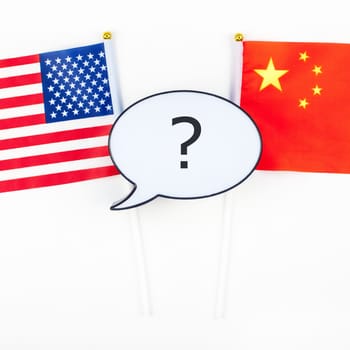 Creative top view flat lay of China and USA flag bubble lightbox with question mark and copy space white background in minimal style. Concept of trade war between USA and China