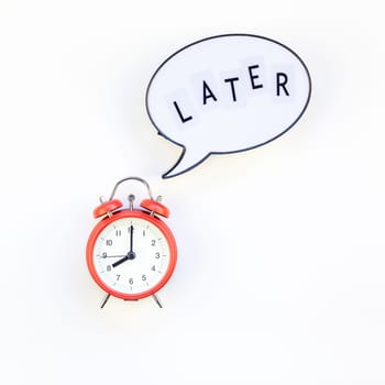 Creative top view flat lay of alarm clock with message Later copy space white background minimal style. Concept of procrastination, time management in business and life