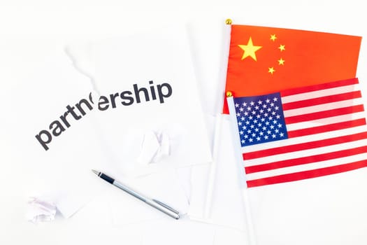 Creative top view flat lay of China and USA flag and broken partnership contract with pen and copy space on white background in minimal style. Concept of trade war between USA and China