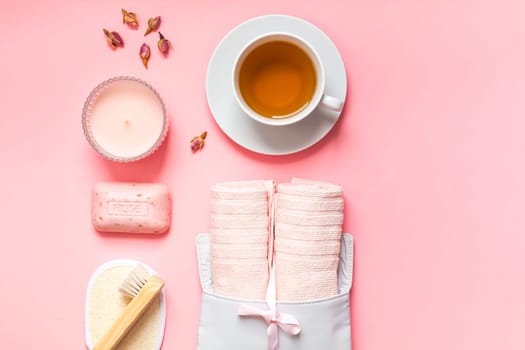 Spa, beauty cosmetics and body care treatment concept copy space. Creative top view flat lay composition bath accessories, rose organic cleansing soap, candle, cup of tea on pink background