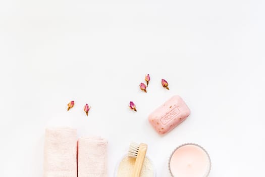 Spa, beauty cosmetics and body care treatment concept with copy space. Creative top view flat lay composition with bath accessories, organic DIY rose soap, flowers and candle on white background