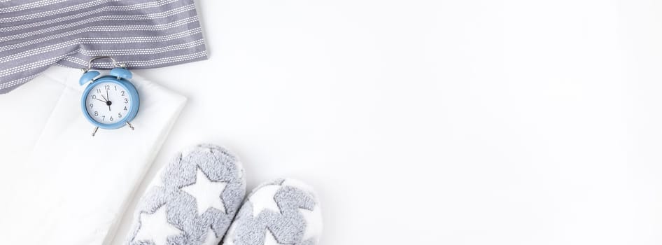 Sleep. Soft fluffy slippers and blue alarm clock isolated on white background. Creative conceptual top view flat lay in minimal style. Rest, good night, insomnia, relaxation, tired, hygge concept