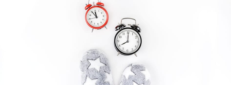 Sleep. Soft fluffy slippers and set of alarm clocks isolated on white background. Creative conceptual top view flat lay in minimal style. Rest, good night, insomnia, relaxation, tired, hygge concept