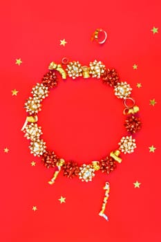 Christmas composition. New Year or Christmas pattern flat lay top view Xmas holiday celebration decorative golden round wreath frame on red background with copy space. Template of greeting card