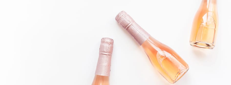 Bottles of rose champagne wine in minimal composition isolated on white background with copy space. Natural light. Template for tasting, degustation invitation card. Top view. Flat lay