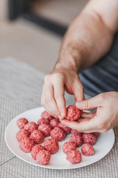 Man hands preparing meatballs with raw mincemeat. Lifestyle close up composition with natural light. Homemade cooking during lockdown, stay home housekeeping sharing concept. Side view with copy space