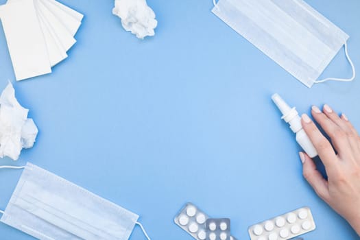 Creative flat lay concept of seasonal spring allergy with napkins, pills, face mask, drops in a bottle and a female hand with copy space background minimal style, template for text