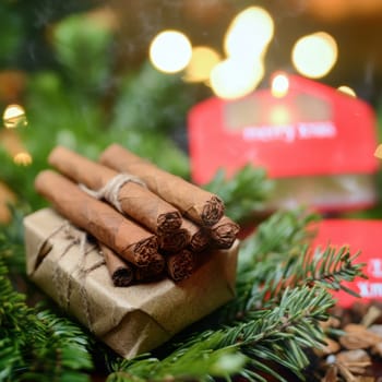 A bundle of cinnamon sticks is tied neatly beside a small wrapped gift surrounded by fresh greenery and adorned with festive decorations.