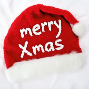 A cheerful red hat featuring white text that reads Merry Xmas perfect for holiday celebrations and festive occasions.