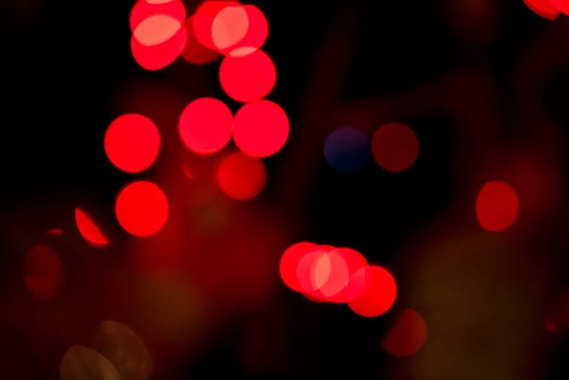 Red Christmas garland blurred and defocused with bokeh on a dark background