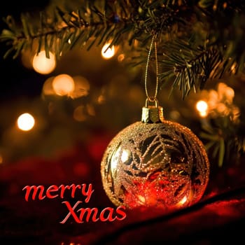 A festive ornament dangles from a tree branch illuminated by soft lights creating a warm holiday atmosphere.