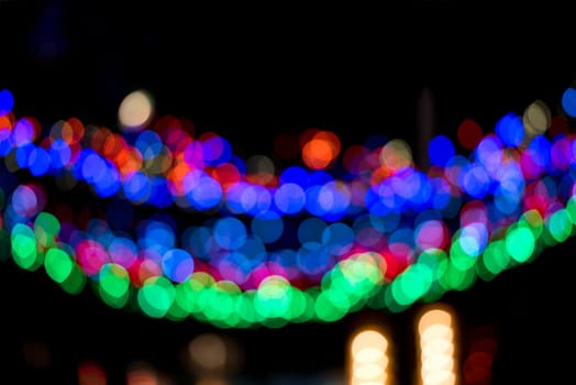Colorful Christmas garland blurred and defocused with bokeh on a dark background