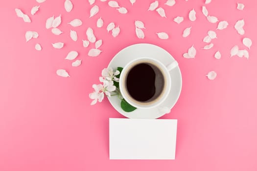 Creative flat lay concept top view of coffee cup and white apple tree flowers petals on pastel pink background with postcard mock up and copy space in minimal style, template for text