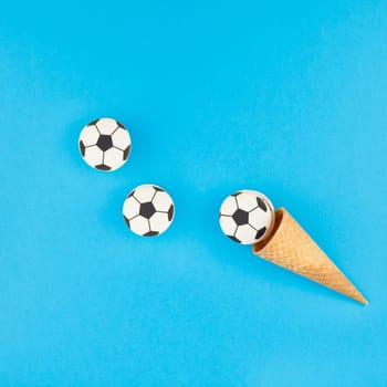 Square Creative flat lay top view of ice cream waffle cones with soccer balls macarons on bright bold blue background with copy space in minimal style, concept of football games for children birthday