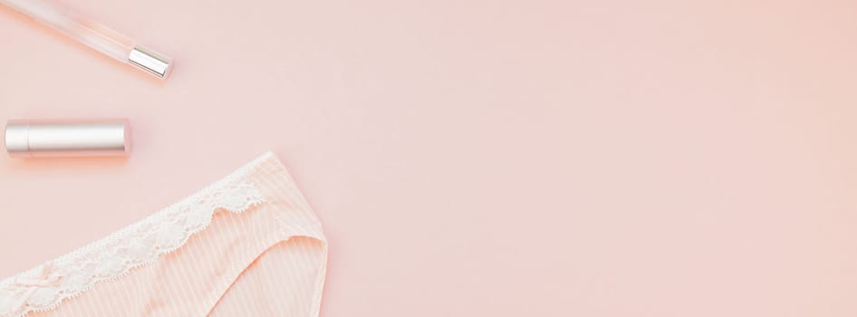Feminine flat lay set of female panties and accessories, perfumes, lipstick on pastel pink color long wide banner for fashion blog and social media with copy space for text