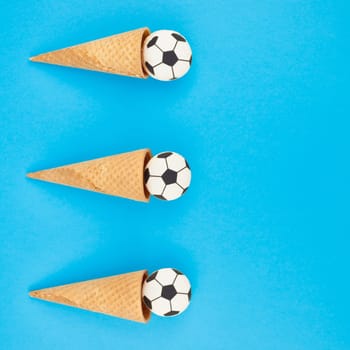 Square Creative flat lay top view of ice cream waffle cones with soccer balls macarons on bright bold blue background with copy space in minimal style, concept of football games for children birthday