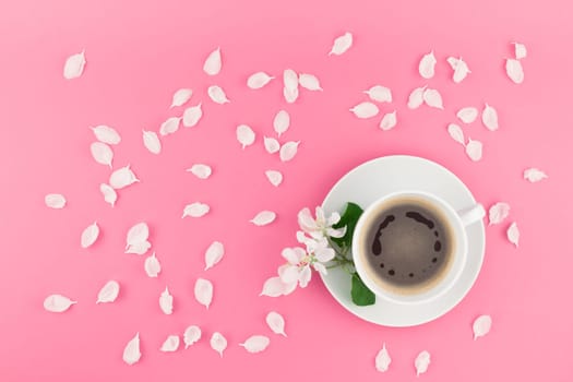 Creative flat lay concept top view of coffee cup and white apple tree flowers petals on pastel pink background with copy space in minimal style, template for text