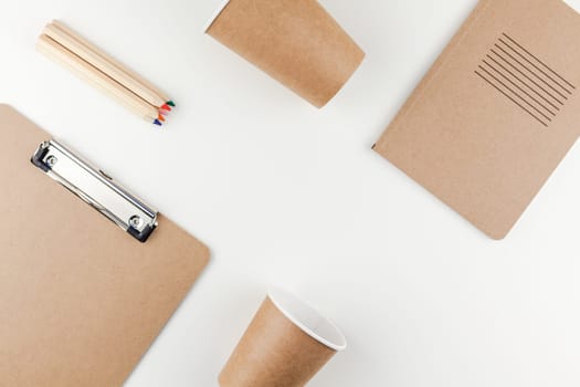Creative top view flat lay of workspace desk styled recycled brown design office supplies and coffee cups with copy space white table background minimal eco style. Concept of environmental protection