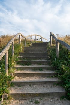 A staircase leading up in the sand dunes with beach grass and blue sky