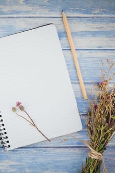 Top view of autumn dry flowers with grass thanksgiving background over blue toned wooden table with notebook mock up and copy space in rustic style, template for text