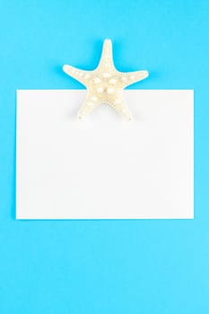 Creative flat lay concept of summer travel vacations. Top view of seashells and starfish on turquoise blue background with postcard mock up and copy space in minimal style, template for text
