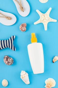 Creative flat lay concept of summer travel vacations. Top view of seashells and starfish on turquoise blue background with sunscreen blank bottle mock up and copy space in minimal style
