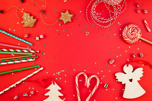 New Year or Christmas decoration flat lay top view Xmas holiday celebration handmade decor wooden toys sweets golden stars glitter on red paper background. Template frame for greeting card your design
