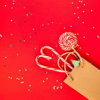 New Year or Christmas decoration flat lay top view Xmas holiday celebration shopping concept decor sweets golden stars glitter on red paper background. Square Template frame greeting card your design