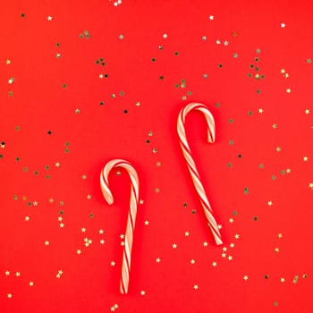 New Year or Christmas decoration flat lay top view Xmas holiday celebration handmade decor sweets golden stars glitter on red paper background. Square Template frame for greeting card your design