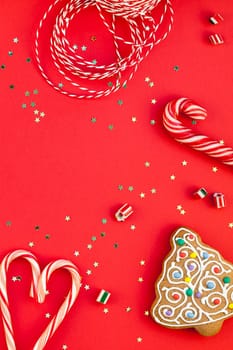 New Year or Christmas decoration flat lay top view Xmas holiday celebration handmade decor wooden toys sweets golden stars glitter on red paper background. Template frame for greeting card your design