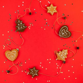 New Year or Christmas decoration flat lay top view Xmas holiday celebration handmade decor sweets golden stars glitter on red paper background. Square Template frame for greeting card your design