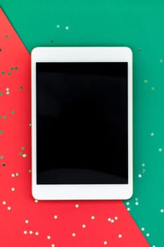 Creative New Year or Christmas tablet PC mockup flat lay top view Xmas holiday celebration mobile device Ipad on red green paper background. Template mock up 2019 2020