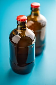 Two beer bottles on a blue background.