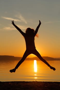The girl jumped up high at sunset by the sea