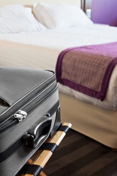 Hotel room with a suitcase on the luggage place and the bed