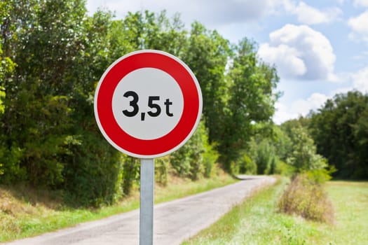 Traffic sign of 3,5 tons weigh restriction on a rural road background