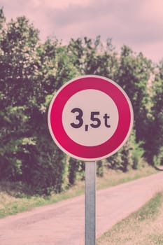 Traffic sign of 3,5 tons weigh restriction on a rural road background