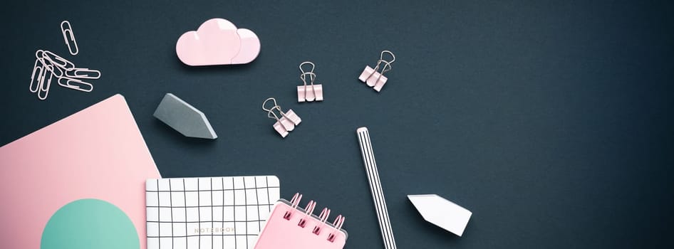 Top view flat lay feminine desk workspace styled pink colored objects design office supplies with copy space on black background. Template for blog social media