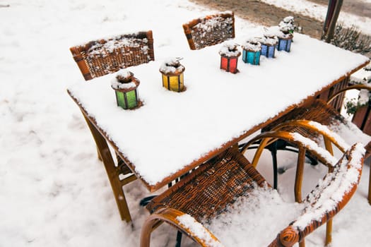Color lamps on street cafe table at snow winter. small GRIP