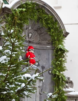 Famous statue of Manneken Pis in Brussels, Belgium wearing Santa Claus clothing for Christmas.
