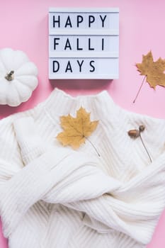Creative autumn flat lay top view white cozy sweater pumpkin leaves lightbox Happy fallidays text on millennial pink background copy space minimal style Fall season composition for feminine blog